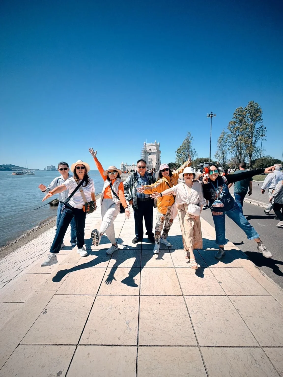 Tour group posing on the riverside promenade by Belém Tower in Lisbon