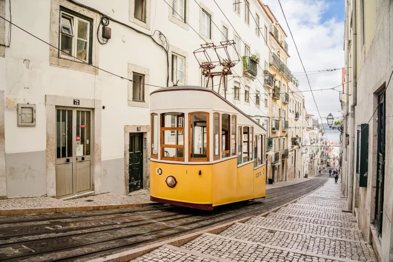 Yellow tram winding through a narrow street in Lisbon's old town