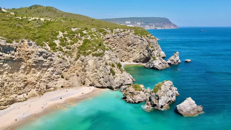 Turquoise water and rocky cliffs at Ribeiro do Cavalo beach near Sesimbra