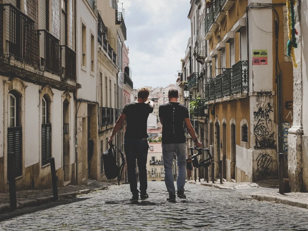 Two travelers walking down a cobbled street in Lisbon's old town