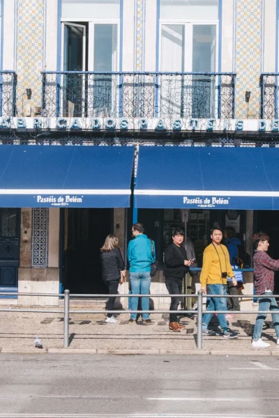 The Pastéis de Belém bakery storefront in Lisbon with a classic tuk tuk parked outside